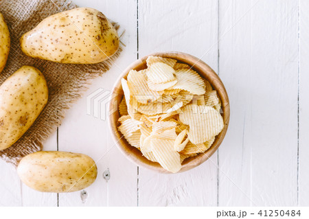 Crispy potato chips in a wooden bowl on wooden Crispy potato chips in a wooden bowl on wooden 41250484