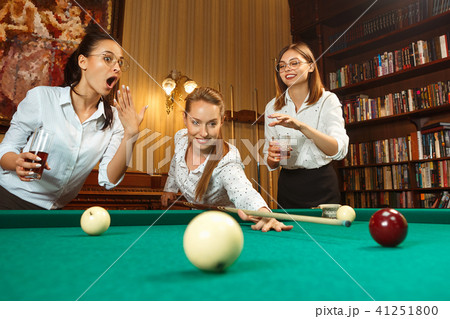 Young women playing billiards at office after work. Young women playing billiards at office after work. 41251800