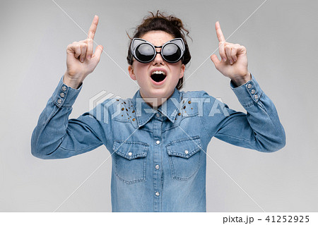 Young brunette girl in black glasses. Cat glasses. The hair is gathered in a bun. The girl points Young brunette girl in black glasses. Cat glasses. The hair is gathered in a bun. The girl points 41252925