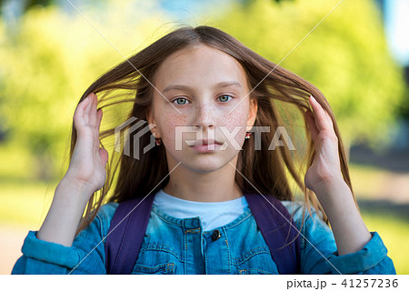 Beautiful teen girl. Summer in nature. Correct the long golden hair. He looks closely at frame. On 41257236