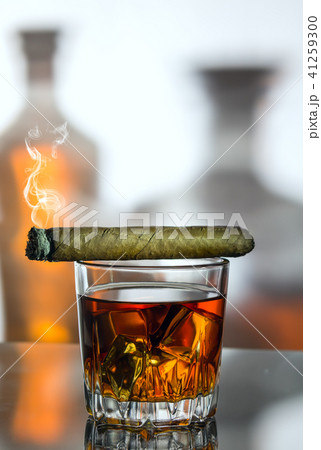 A glass of whiskey and a smoke cigar A glass of whiskey and a smoke cigar 41259300