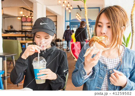 リゾート地のベーカリーカフェで食事を楽しむ若い2人の女性 リゾート地のベーカリーカフェで食事を楽しむ若い2人の女性 41259502
