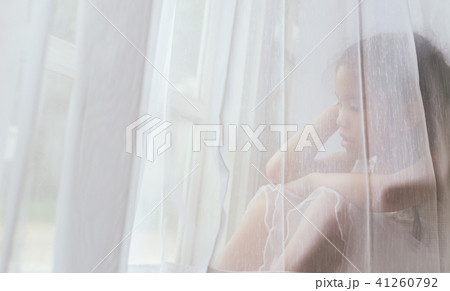 Depressed Asian child near window at home Depressed Asian child near window at home 41260792