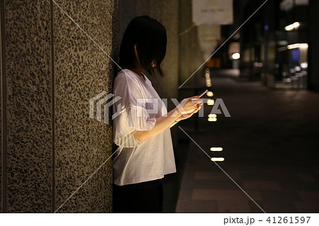 夜に壁に寄りかかってスマートフォンを見る女性 夜に壁に寄りかかってスマートフォンを見る女性 41261597