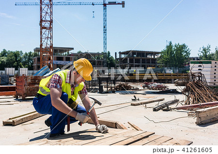 Side view of a young worker hammering a nail into wood during work 41261605