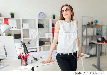 Beautiful young girl in an office is standing near a table. 41265626