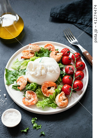 Salad with burrata cheese, shrimps, lettuce and tomatoes on a white plate Salad with burrata cheese, shrimps, lettuce and tomatoes on a white plate 41274474