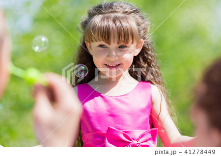 Little girl is playing with soap bubbles. 41278449