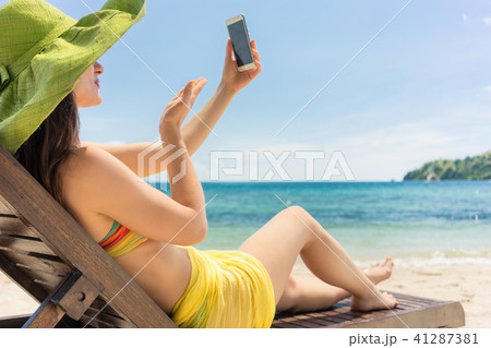 Attractive young woman sending a love message through a selfie on the beach Attractive young woman sending a love message through a selfie on the beach 41287381