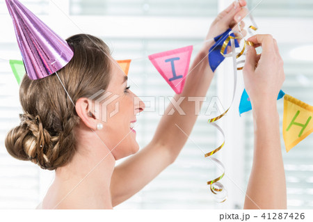 Happy adult woman hanging decorations for her birthday party 41287426