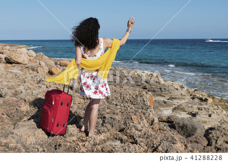 Woman with dress of roses waving on a rocky coast  41288228