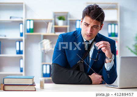 Businessman with broken arm working in office 41289457