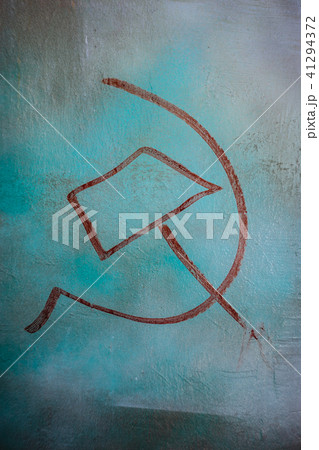 Red hammer and sickle painted on a blue colored wall. Vertical orientation 41294372