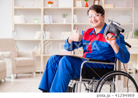 Disabled man working with handsaw at home 41294969