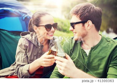 happy couple clinking drinks at campsite tent 41300363