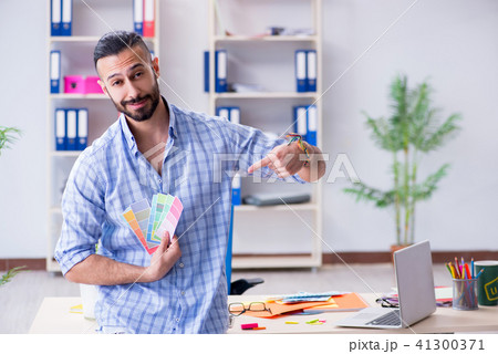 Young designer working in his studio on new project Young designer working in his studio on new project 41300371