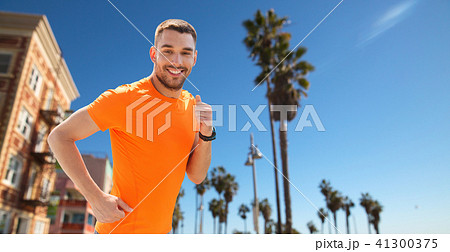 smiling young man running at summer seaside 41300375