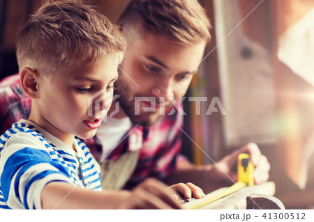 father and son with ruler measure wood at workshop 41300512
