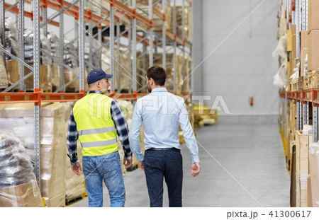 worker and businessman walking along warehouse 41300617
