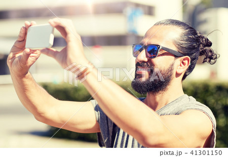 man taking video or selfie by smartphone in city 41301150