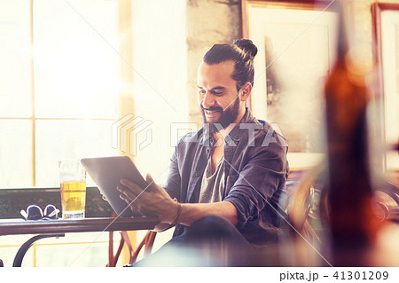 man with tablet pc drinking beer at bar or pub 41301209