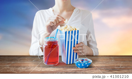 woman eating popcorn with drink in glass mason jar woman eating popcorn with drink in glass mason jar 41301210