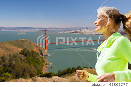 woman with earphones running over san francisco woman with earphones running over san francisco 41301277