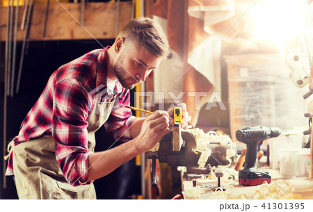 carpenter with ruler measuring plank at workshop carpenter with ruler measuring plank at workshop 41301395