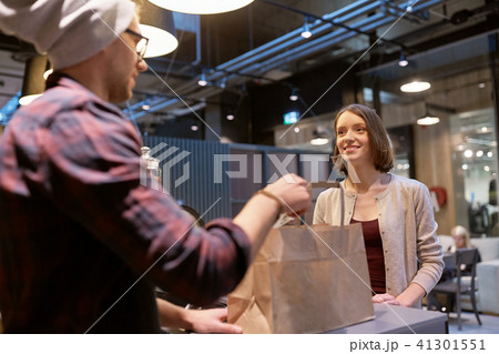 seller giving paper bag and money to woman at cafe seller giving paper bag and money to woman at cafe 41301551