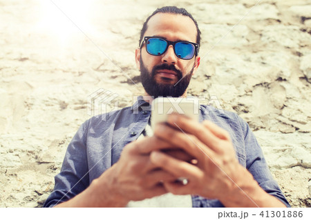 man texting message on smartphone at stone wall 41301886
