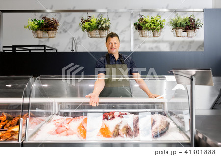 male seller showing seafood at fish shop fridge male seller showing seafood at fish shop fridge 41301888