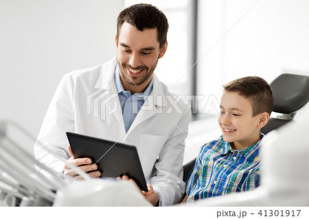 dentist showing tablet pc to kid patient at clinic 41301917