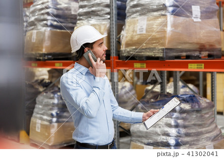 businessman calling on smartphone at warehouse businessman calling on smartphone at warehouse 41302041
