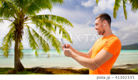 smiling young man with smartphone and earphones 41302335