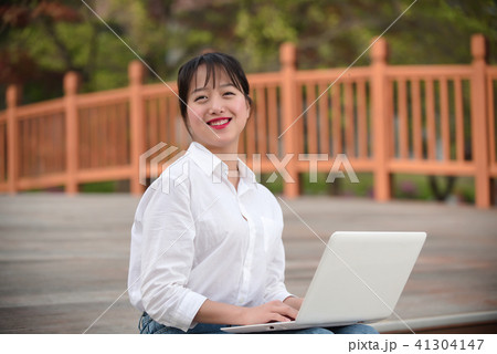 女子大生 屋外 ノートパソコンの写真素材