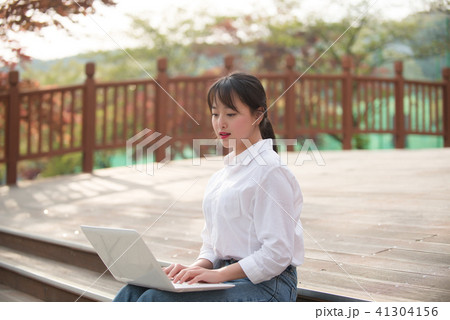 女子大生 屋外 ノートパソコンの写真素材