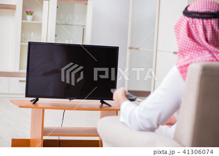 Arab businessman watching tv at home Arab businessman watching tv at home 41306074