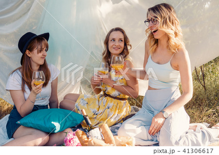 Group of girls friends making picnic outdoor. They have fun Group of girls friends making picnic outdoor. They have fun 41306617