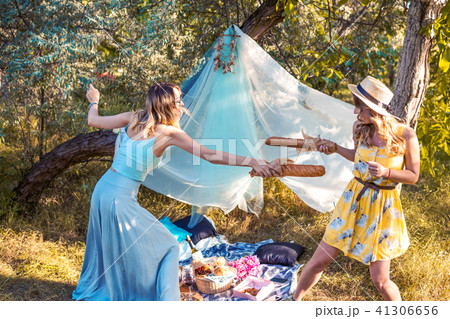 Playful girls fighting with bread baguette making picnic 41306656