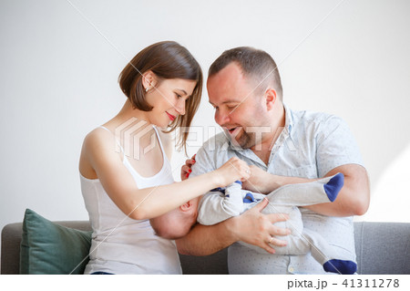 Picture of young parents with newborn baby sitting on sofa Picture of young parents with newborn baby sitting on sofa 41311278