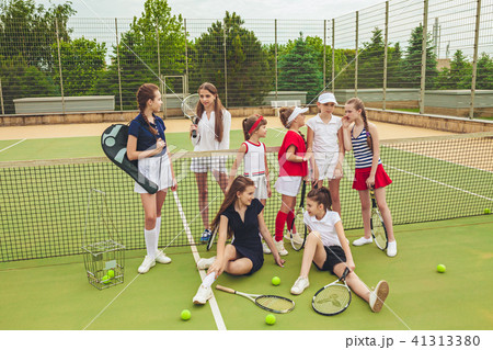 Portrait of group of girls as tennis players holding tennis racket against green grass of outdoor 41313380