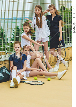 Portrait of group of girls as tennis players holding tennis racket against green grass of outdoor 41313538