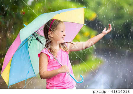 Kid with umbrella playing in summer rain. 41314018