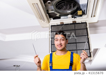 Repairman repairing ceiling air conditioning unit 41315670