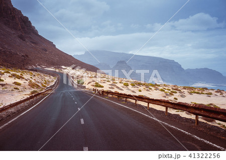 Asphalt road leads between black volcano erosion mountain and white sand dunes. Breathtaking 41322256