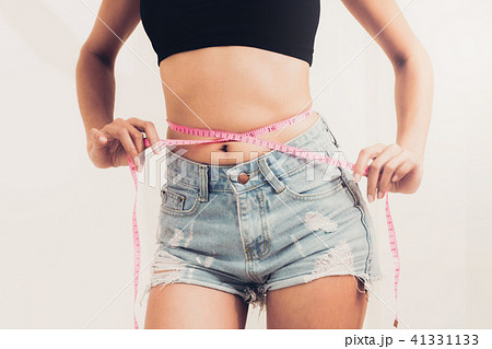 Slim woman measures her waist with measuring tape. Slim woman measures her waist with measuring tape. 41331133