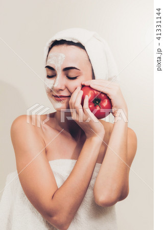 Woman get facial mask with tomato cream extract. 41331144