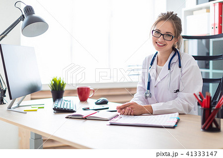 A young girl in a white robe is sitting at the computer desk. 41333147