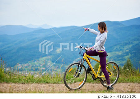 Young happy woman riding bicycle in the mountains at summer day 41335100
