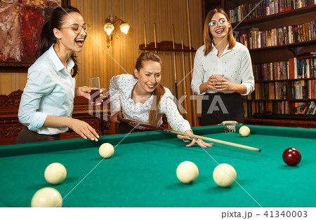 Young women playing billiards at office after work. Young women playing billiards at office after work. 41340003